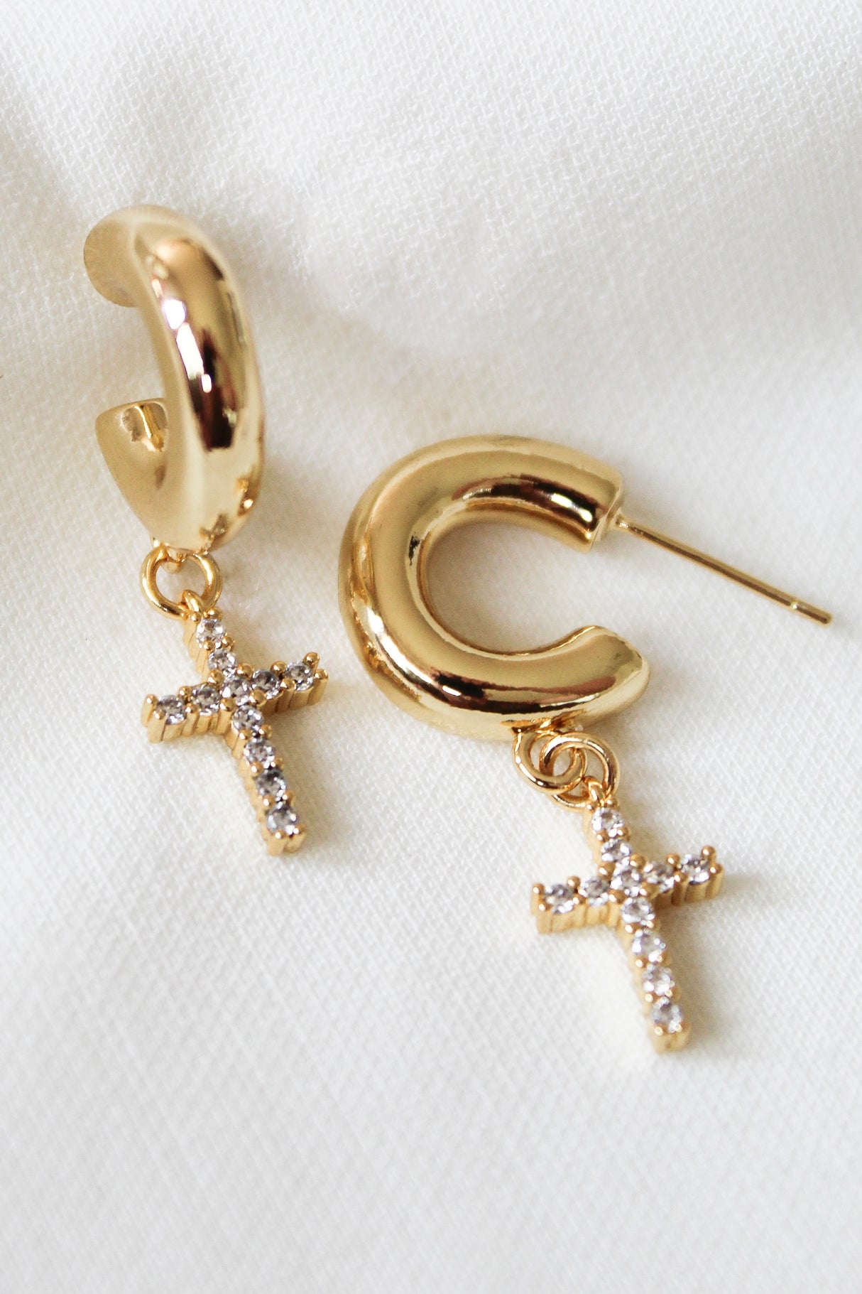The Victoria Hoop by Kinsey Designs Archives: 1.5" gold filled hoops with sparkling cross pendants, displayed on white fabric. Elevate your style—shop this chic sample sale now!.