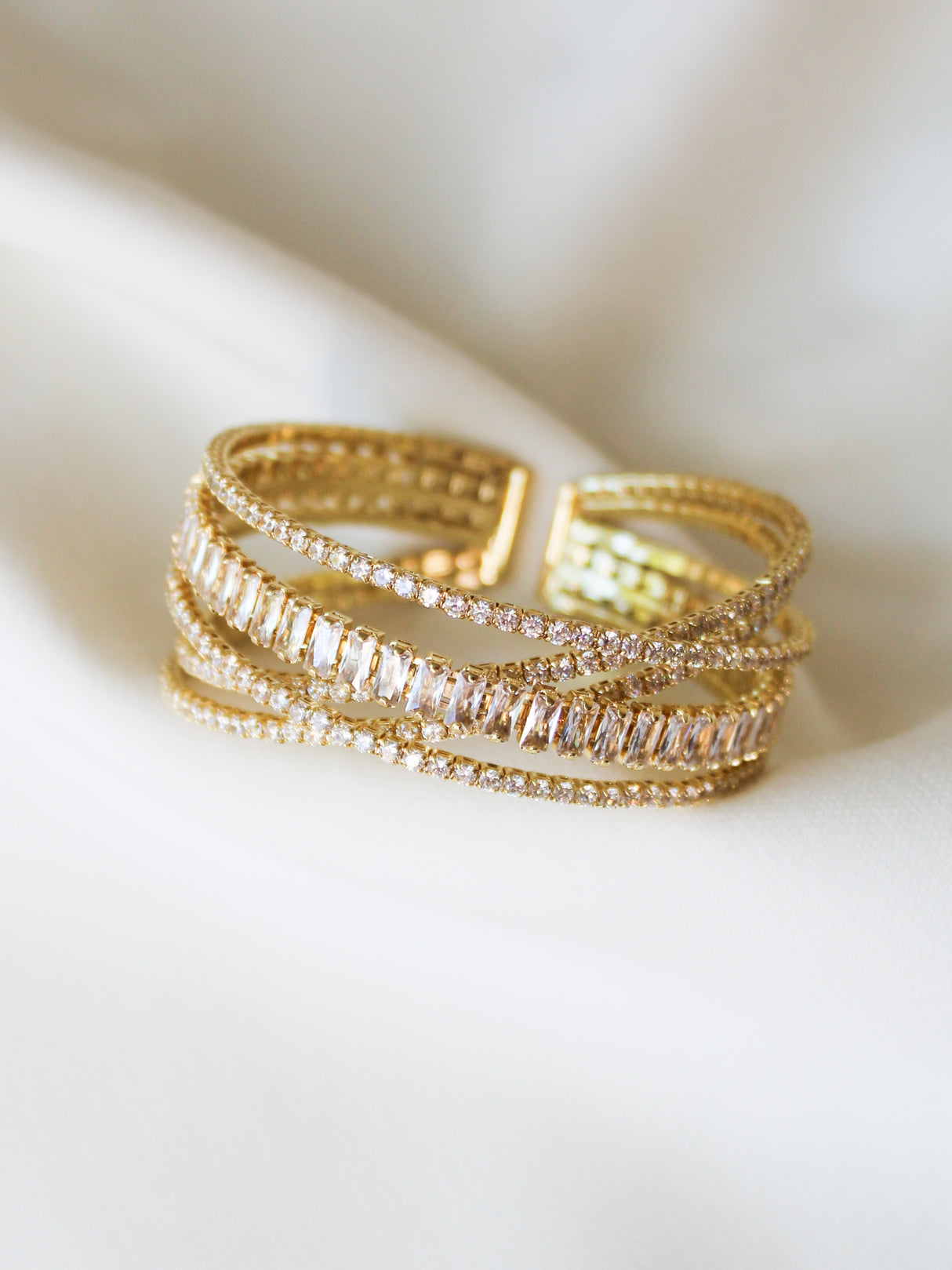 The Zara Cuff Bracelet by Kinsey Designs Archives features crisscrossing gold-filled bands with sparkling clear gemstones. Adjustable for a perfect fit. Displayed on white fabric. Shop now for special sample sale pricing!.