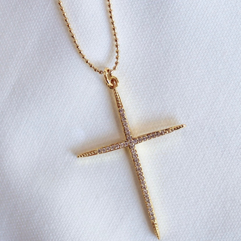 The Meyer Necklace by Kinsey Designs Archives features a gold-filled cross with small diamonds on a delicate 20-inch chain, displayed on white fabric.