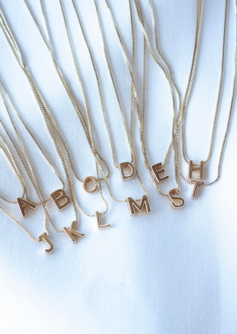 The Kinsey Designs Collection Kinsey Slide Initial Necklace featuring the letter C is displayed on a white fabric background.