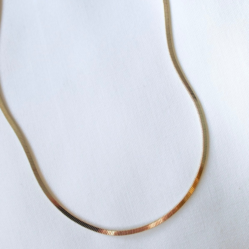The Isla Necklace by Kinsey Designs Archives features an 18" gold-filled herringbone chain, shown on a white fabric background.