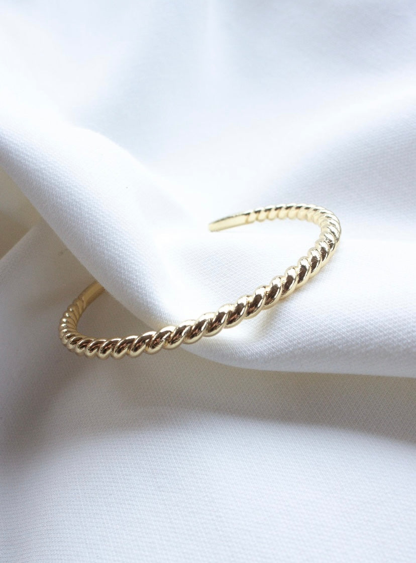 The Fallon Cuff by Kinsey Designs, a gold filled adjustable bangle bracelet, resting on white fabric.