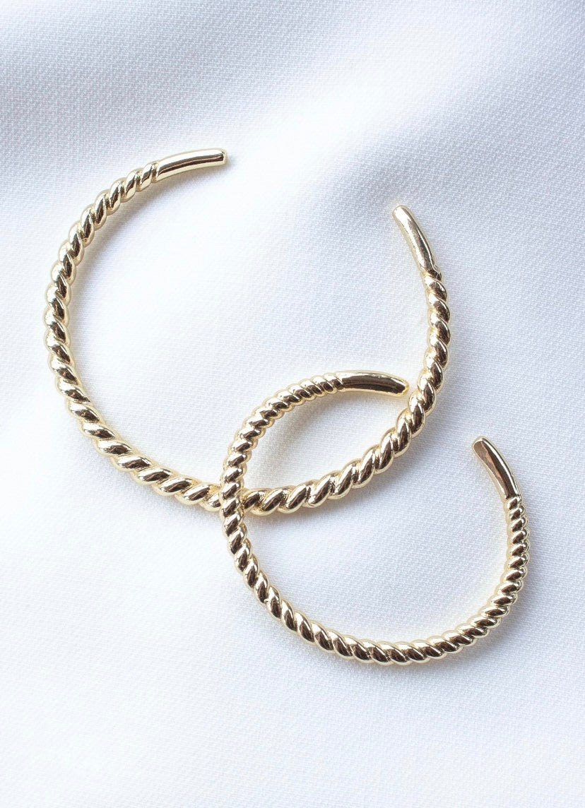 The Fallon Mama & Baby Cuff Set by Kinsey Designs features two gold twisted hoop earrings on a white fabric background, paired with an adjustable gold-filled, nickel-free bracelet.