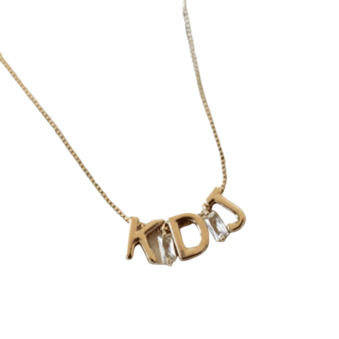 Kinsey Designs' Gold Letter Slide Charms form the initials "KDJ" on this customizable necklace, featuring a delicate chain and stylish letter pendants against a white background.