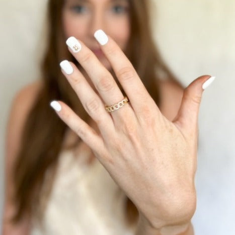 A woman with white painted nails displays her hand wearing the Ava Lux Ring by Kinsey Designs Archives, with her face softly blurred in the background.