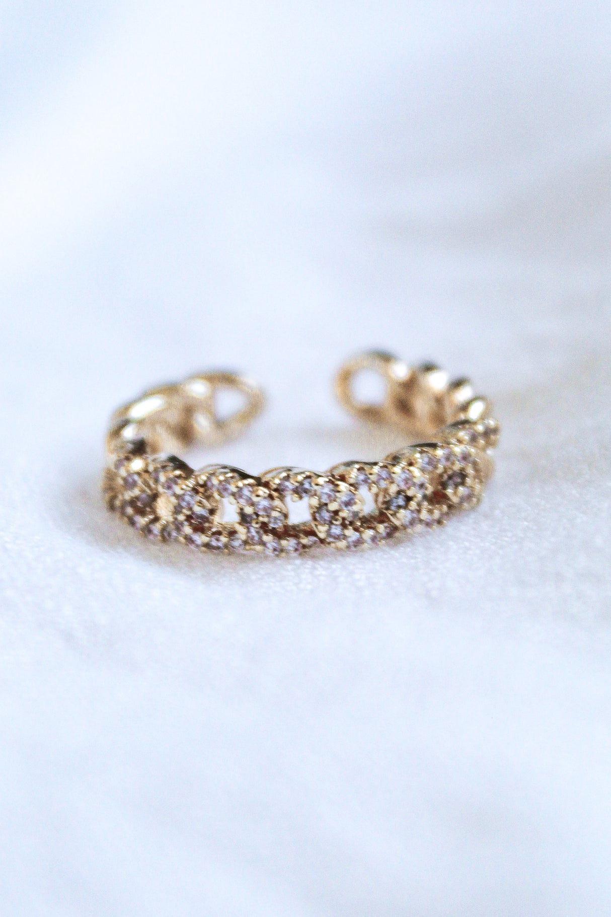 The Ava Lux Ring by Kinsey Designs Archives is a gold-plated, chain-style adjustable ring adorned with sparkling cubic zirconia, shown on a soft white background.