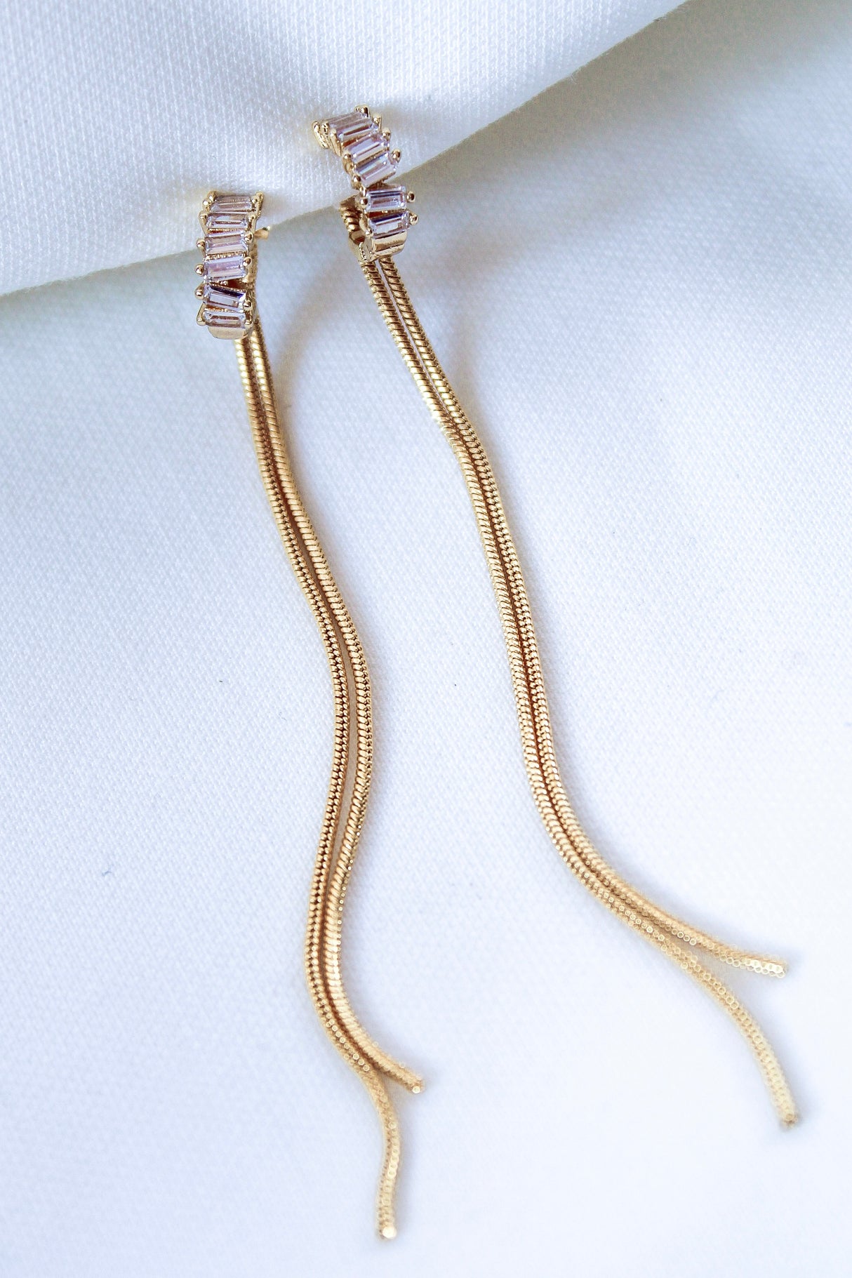 The Callie Earring by Kinsey Designs Archives features 3.5-inch gold filled earrings with rectangular cubic zirconia accents, shown on a white fabric background.