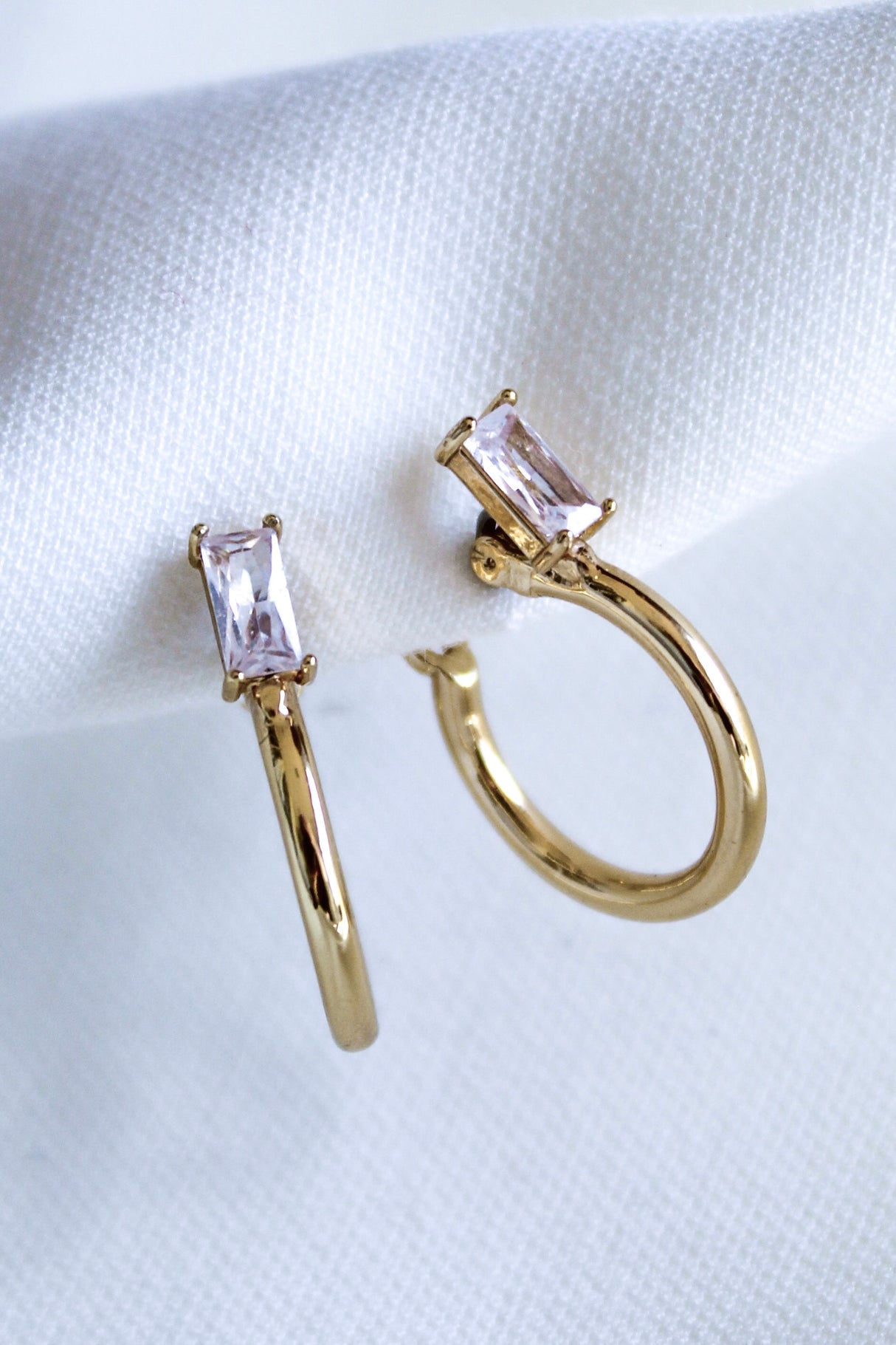 The Darra Hoop Mini by Kinsey Designs Archives are gold plated hoop earrings with a .75" diameter, adorned with rectangular clear cubic zirconia gemstones, displayed on a white fabric background.