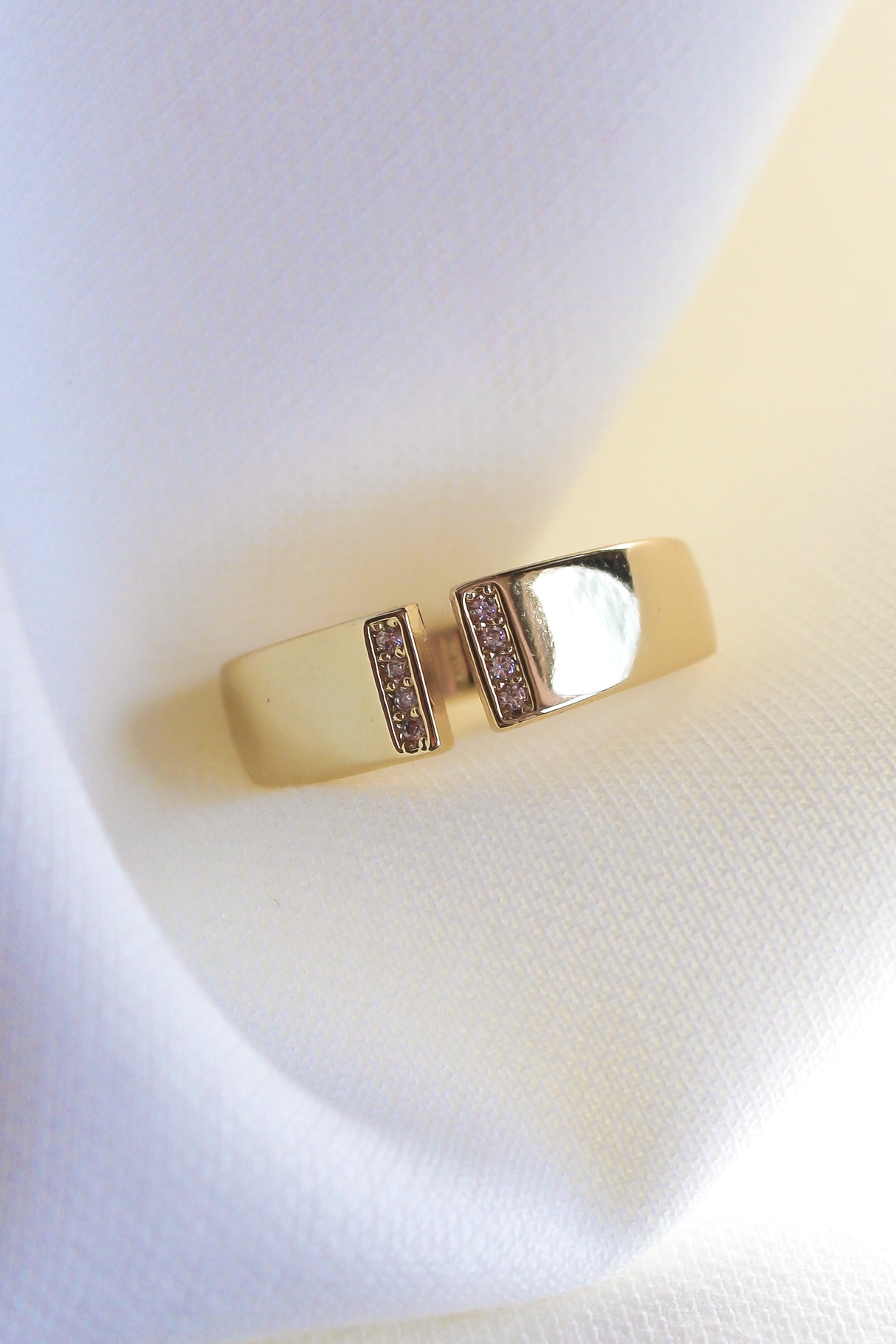 The Dean Ring by Kinsey Designs Archives features two parallel bars with sparkling cubic zirconia on a gold-plated band, shown on white textured fabric. Size 6.