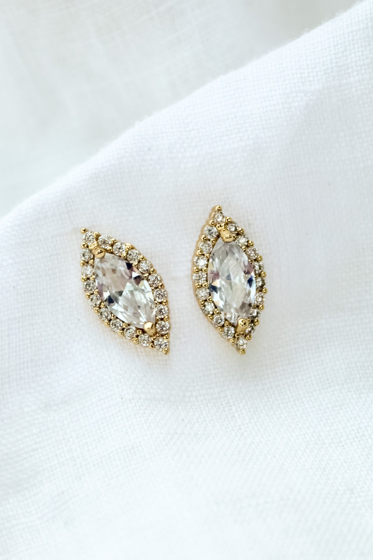 The Dina Post marquise-shaped stud earrings by Kinsey Designs Archives are shown on a white fabric background.