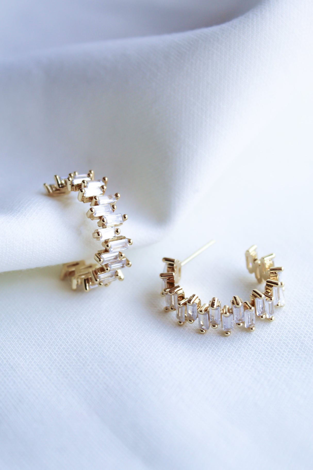 The Ettie Hoop by Kinsey Designs Archives features 1" gold-filled hoops adorned with rectangular cubic zirconia, elegantly displayed on white fabric.