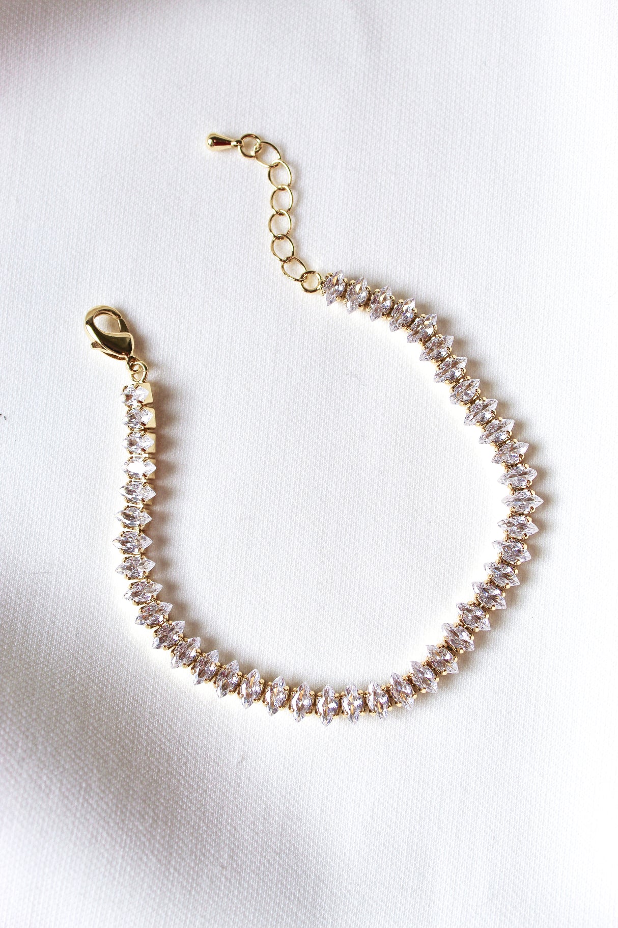 The Gator Bracelet by Kinsey Designs Archives features a gold filled 6.5-inch chain with sparkling gemstones and an extender, displayed on a white fabric background.