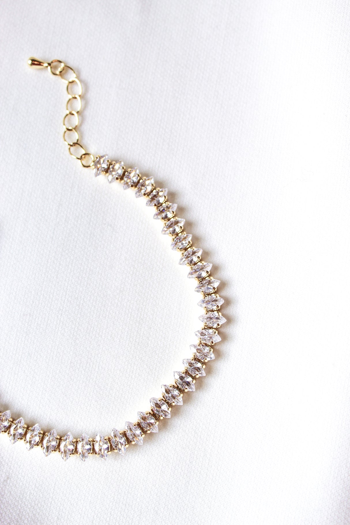 The Gator Bracelet by Kinsey Designs Archives features a 6.5-inch gold filled chain with a clasp, accented by diamonds, and is displayed against a white fabric background.