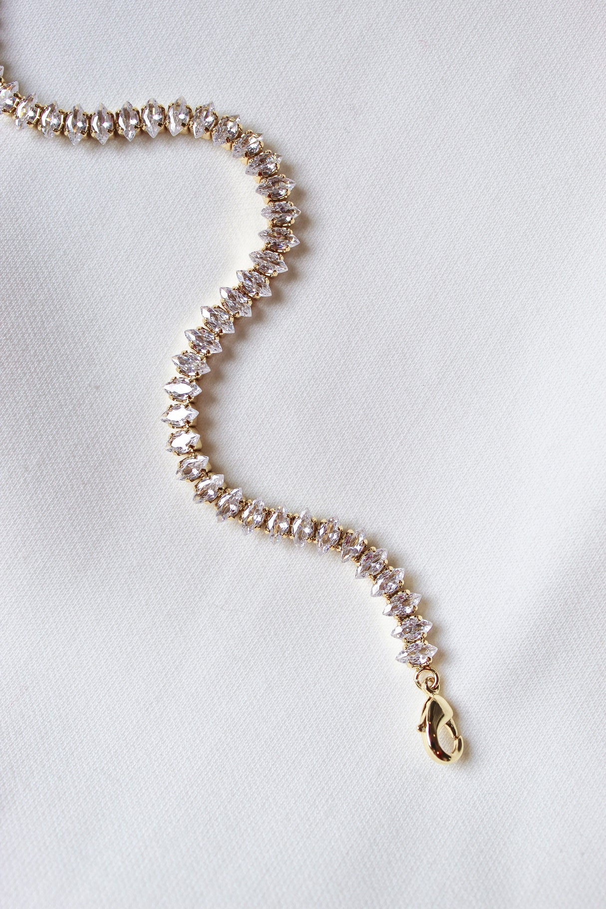 The Gator Bracelet by Kinsey Designs Archives features a gold filled chain with sparkling stones, a 6.5-inch length, and an extender for a perfect fit, shown on a white fabric background.