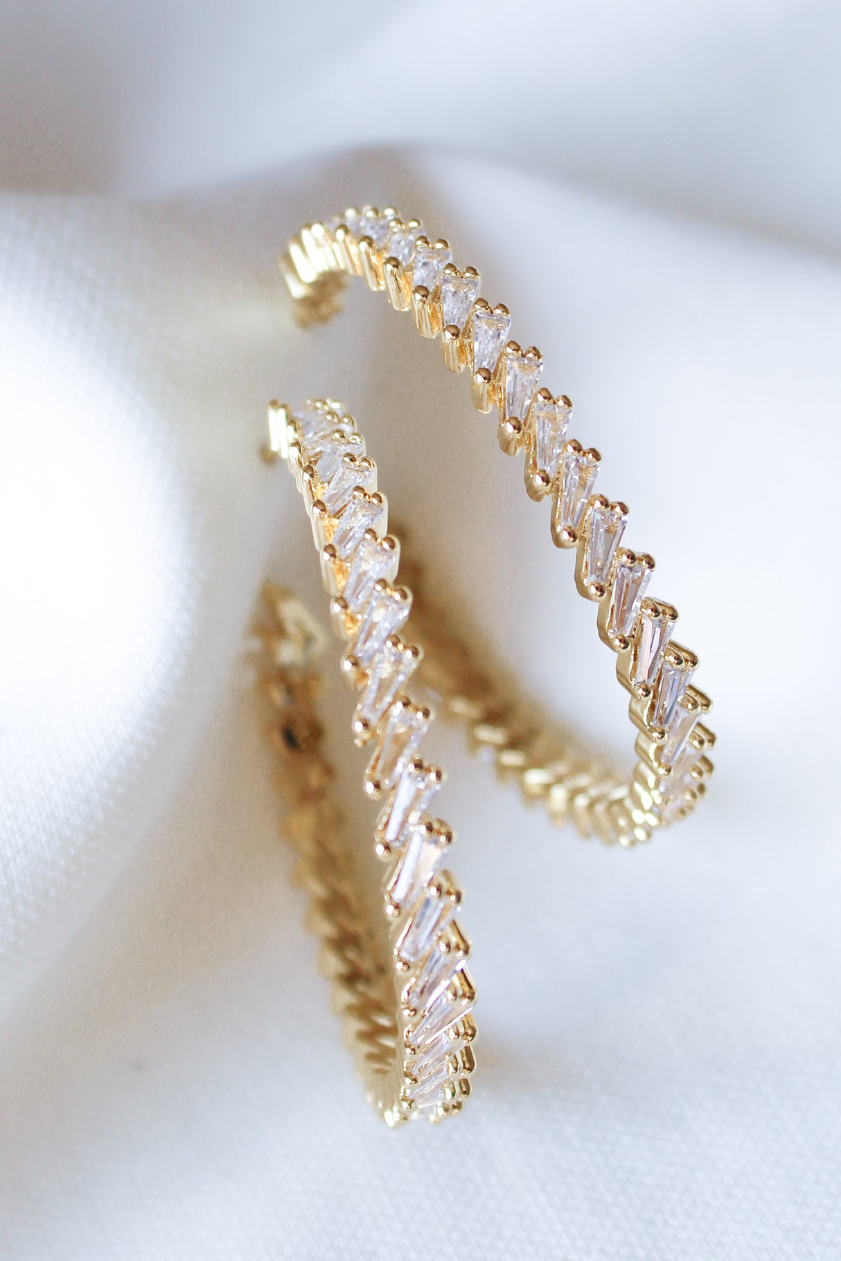 The Graze Hoop by Kinsey Designs Archives features zigzag-set cubic zirconia in gold fill, shown on white fabric. Add sparkle to any look—shop now at our sample sale!.