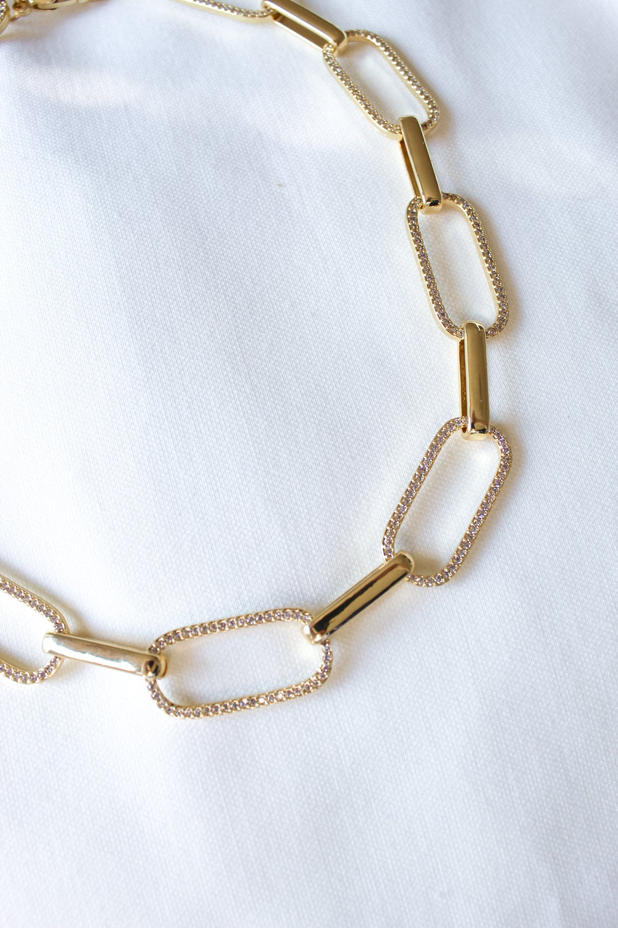 Close-up of the Jameson Necklace by Kinsey Designs, featuring gold rectangular links on a white fabric background—a bold statement piece for any occasion.