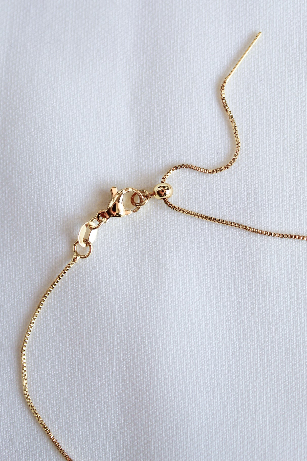 A close-up of the Kinsey Designs Archives MAMA Slide Necklace, a 14k gold filled chain with an adjustable Italian closure and lobster clasp, displayed on a white textured background.