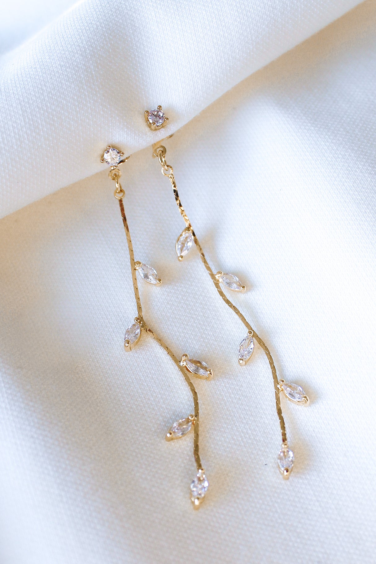 The Parker Earring by Kinsey Designs Archives features gold-filled, branch-style design with cubic zirconia leaves, shown on white fabric—an elegant addition to your style. Shop now at our exclusive sample sale!.