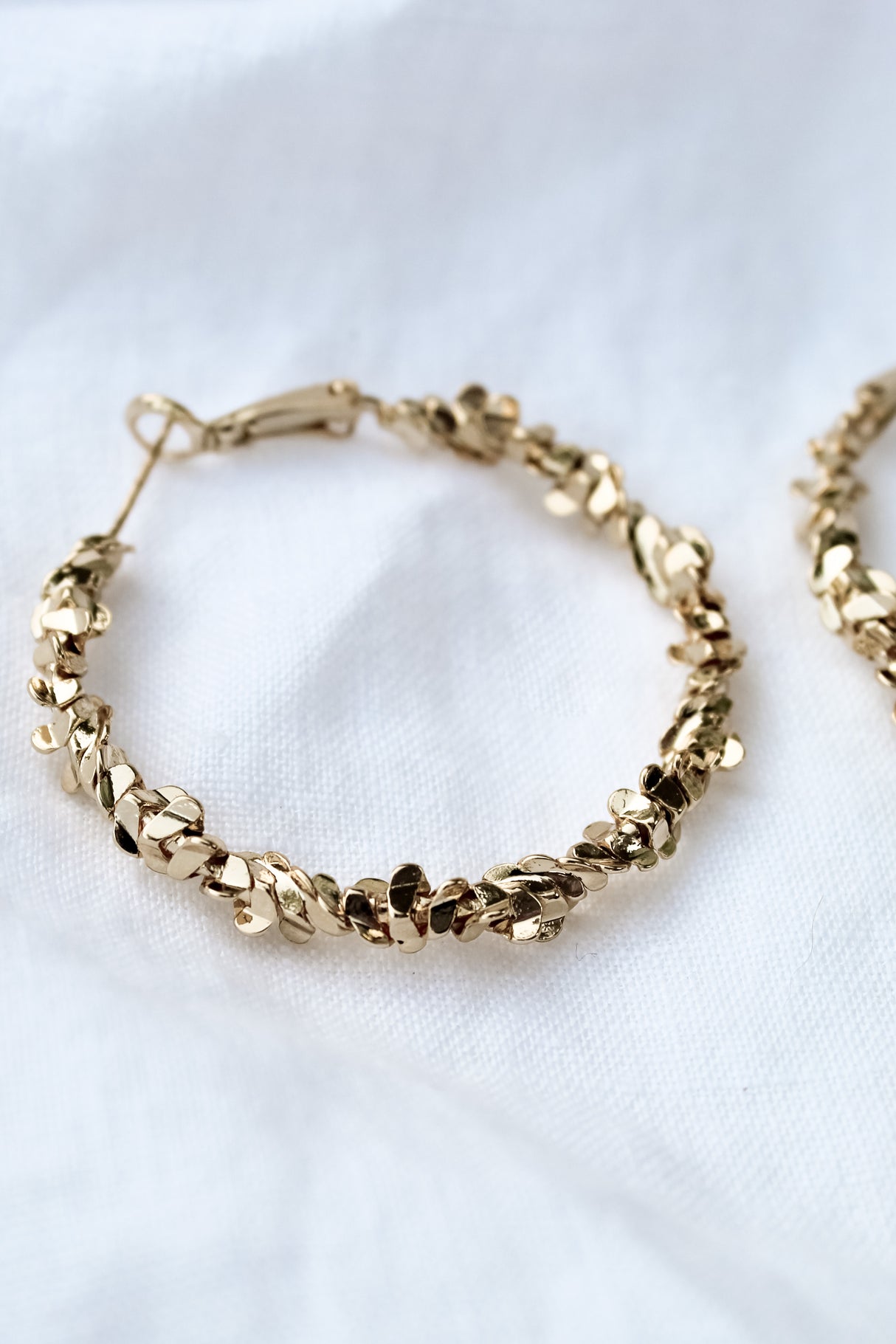 The Reese Hoop by Kinsey Designs Archives is a gold filled earring with leaf-shaped details, 1.5" in diameter, shown on a white fabric background.