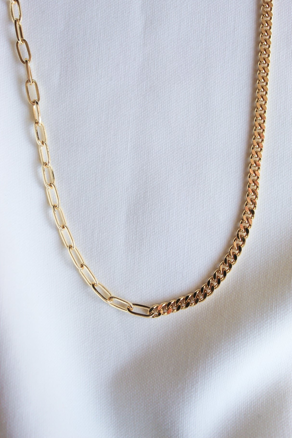 The Saxon Necklace by Kinsey Designs Archives features two distinct gold filled link styles, creating a bold statement chain that's striking against a white fabric background.