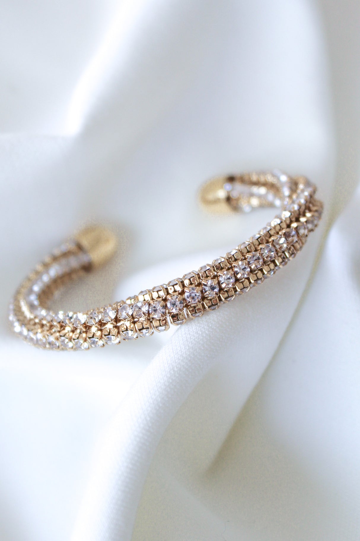 The Smog Cuff by Kinsey Designs Archives is a 16k gold plated brass adjustable bracelet with sparkling Cubic Zirconia, displayed on a white textured fabric background.