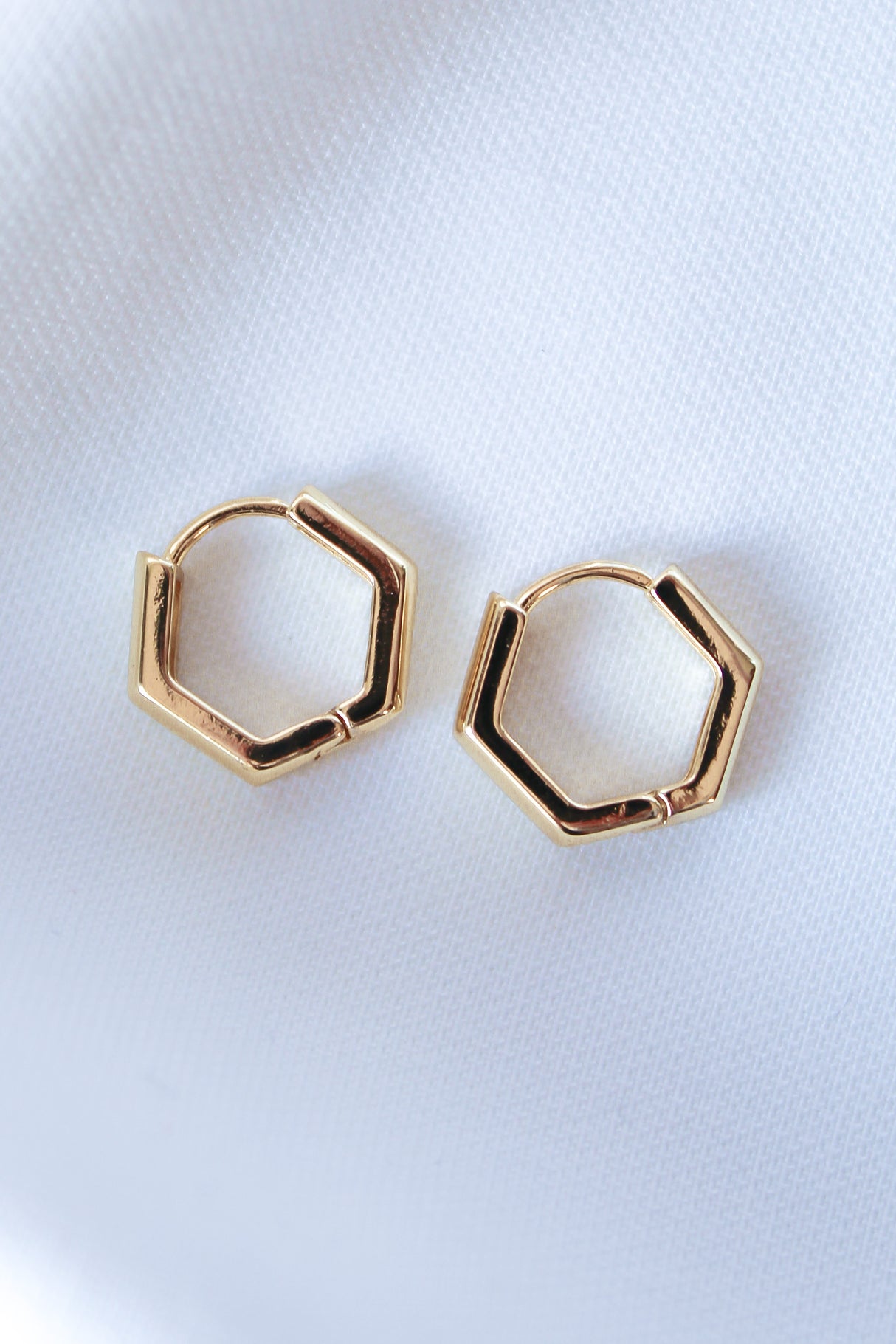 The Theo Hoop by Kinsey Designs Archives features two hexagonal gold-filled earrings displayed on white fabric, available as a final sale.