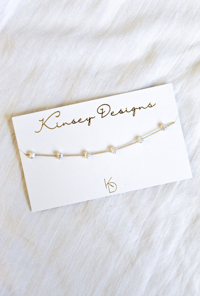The Adalee gold chain bracelet from Kinsey Designs Archives features evenly spaced pearls and comes on a branded card—pairs perfectly with a gold plated or adjustable 14" necklace for a coordinated style.