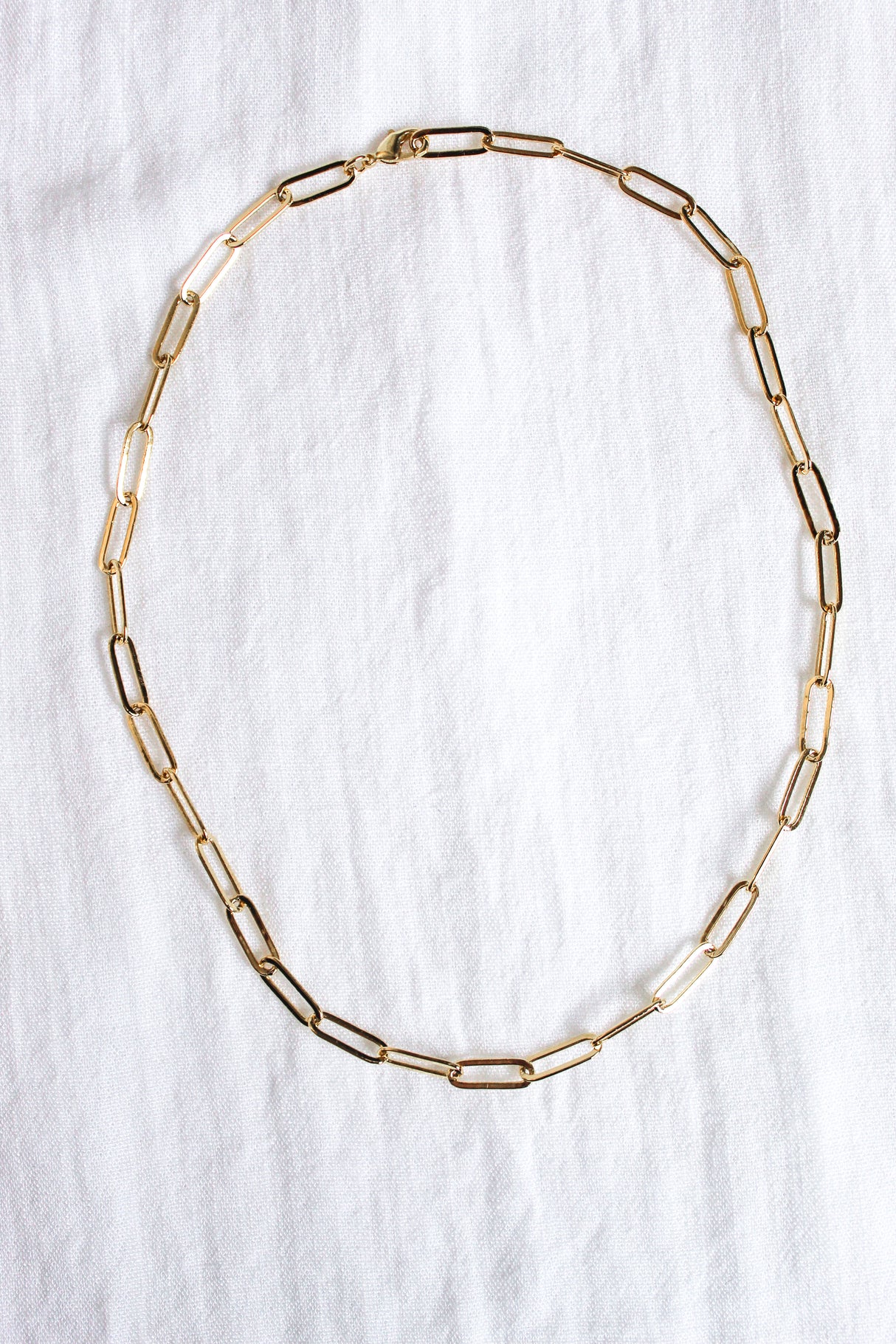 The Maeve Necklace by Kinsey Designs is a stunning gold filled paperclip chain, elegantly displayed on a white fabric background.