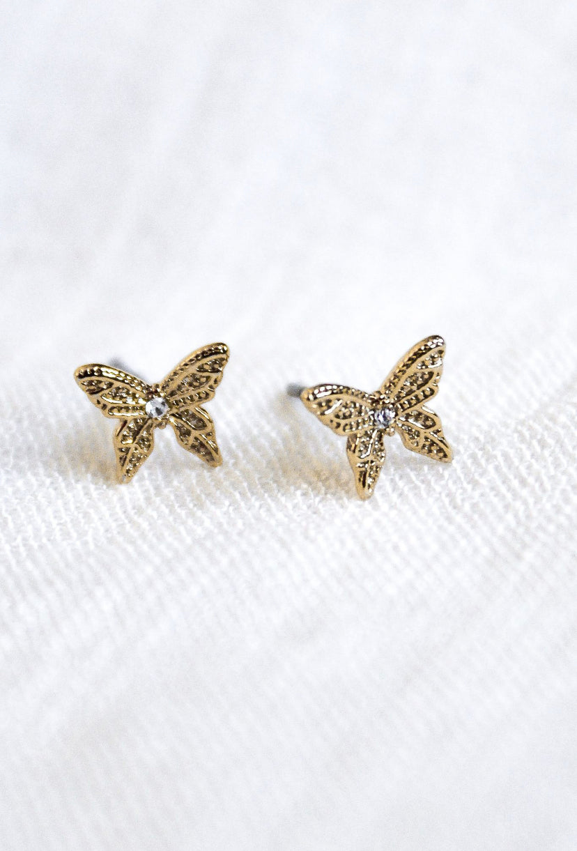 Fleur gold-plated butterfly earrings by Kinsey Designs Archives, adorned with small crystals and shown on white textured fabric. Measurements available upon request.