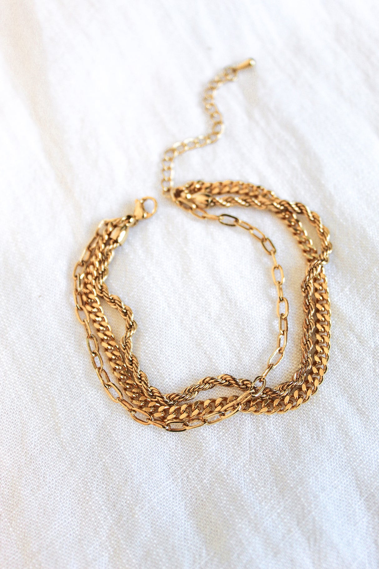 The Emmy Bracelet by Kinsey Designs Archives features gold-plated mixed link styles and a chain extender, displayed on a white fabric background.