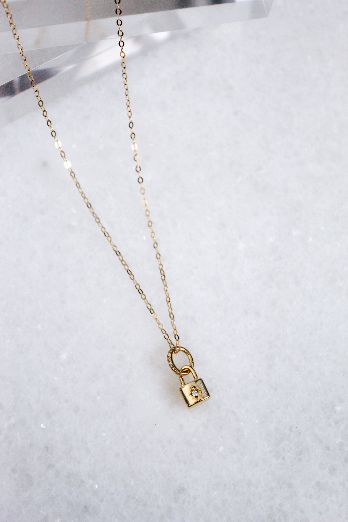 The Blaire Lock Necklace by Kinsey Designs Archives features a small gold-plated brass padlock charm on a 16k gold-filled chain, elegantly displayed on white marble.