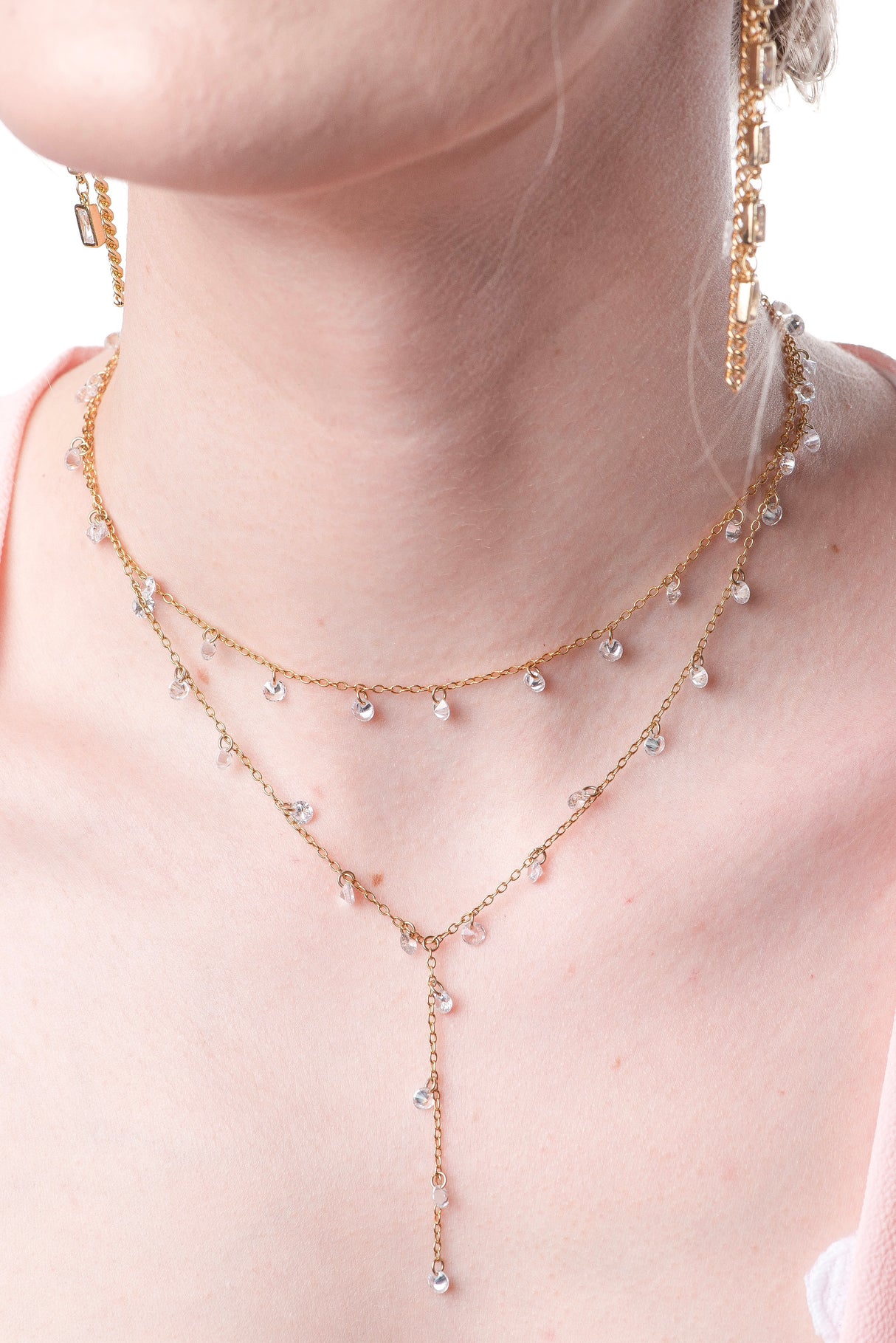The Clare Lariat by Kinsey Designs Archives is an 18k gold plated necklace with small clear CZ charms and an adjustable extender, shown on a fair-skinned model.
