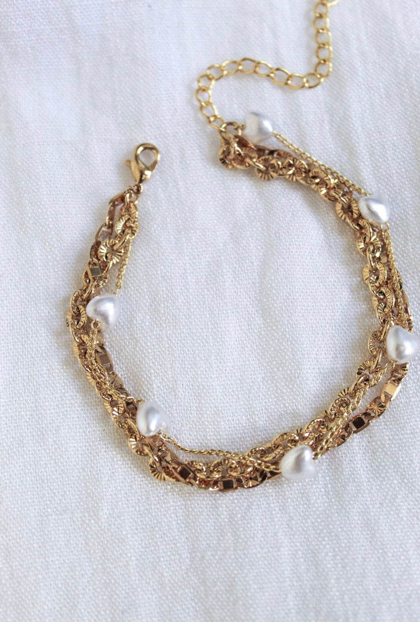 The Beyah Layer Bracelet by Kinsey Designs Archives features a gold plated brass chain with white pearls, elegantly displayed on a white fabric background.