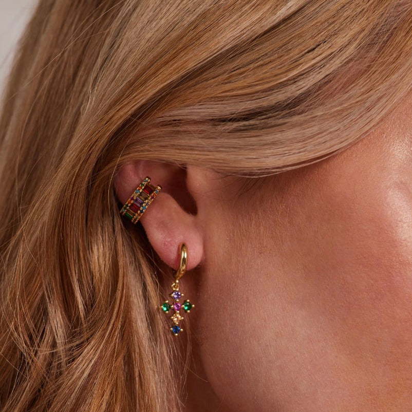 A close-up of a woman's ear wearing the Clementine Ear Cuff by Kinsey Designs Archives, featuring gold-filled metal and multicolored cubic zirconia gemstone flowers.