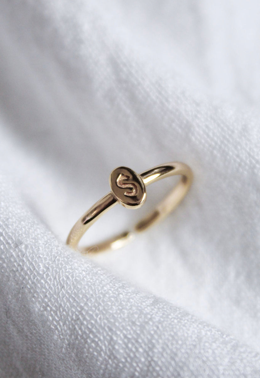 Kinsey Designs Collection's Kinsey Initial Ring features an oval-shaped top engraved with the letter "S," displayed on a white fabric background.
