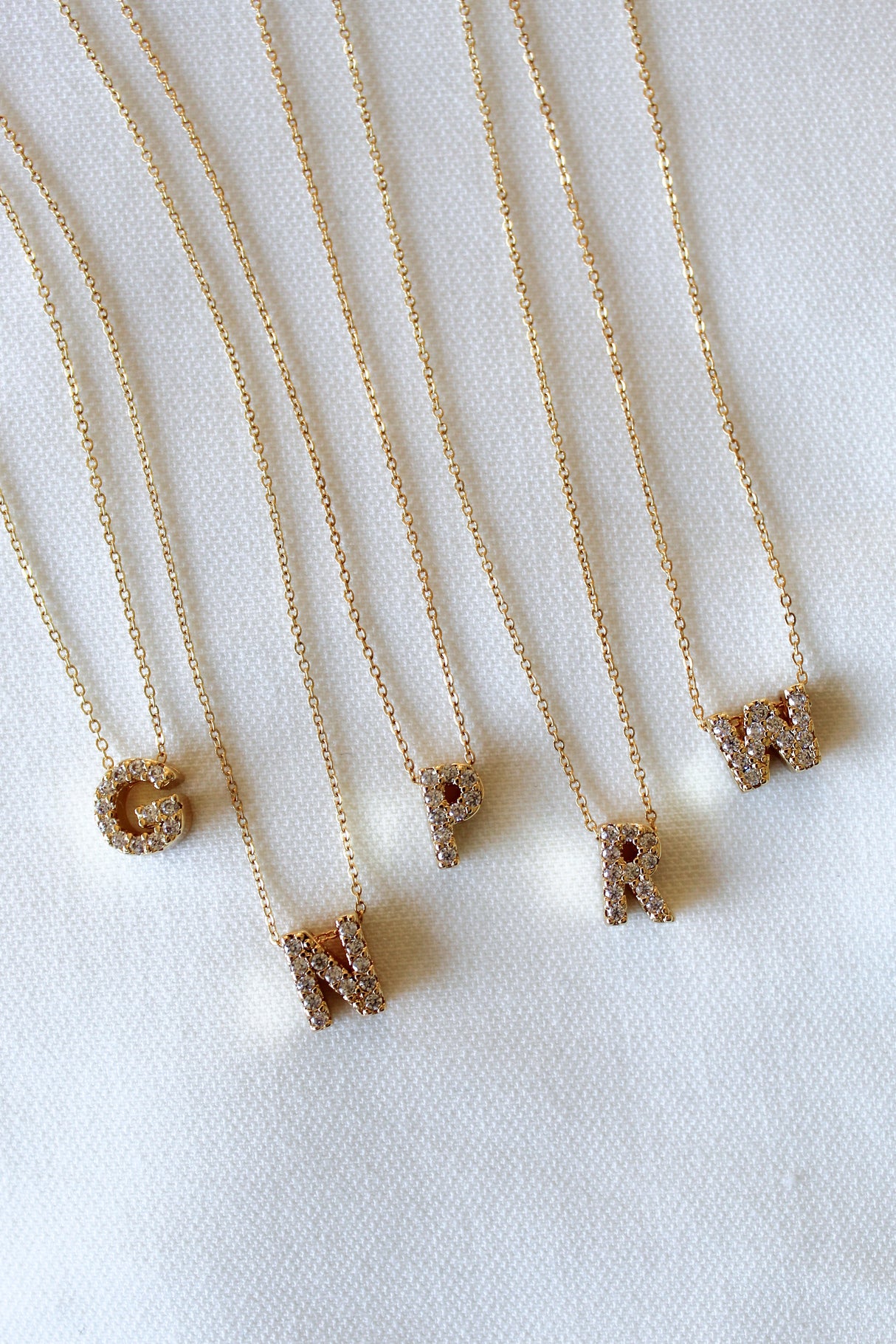 The Kinsey Designs Collection LUX Slide Initial Necklace with a gold letter C pendant is displayed on a white textured background.