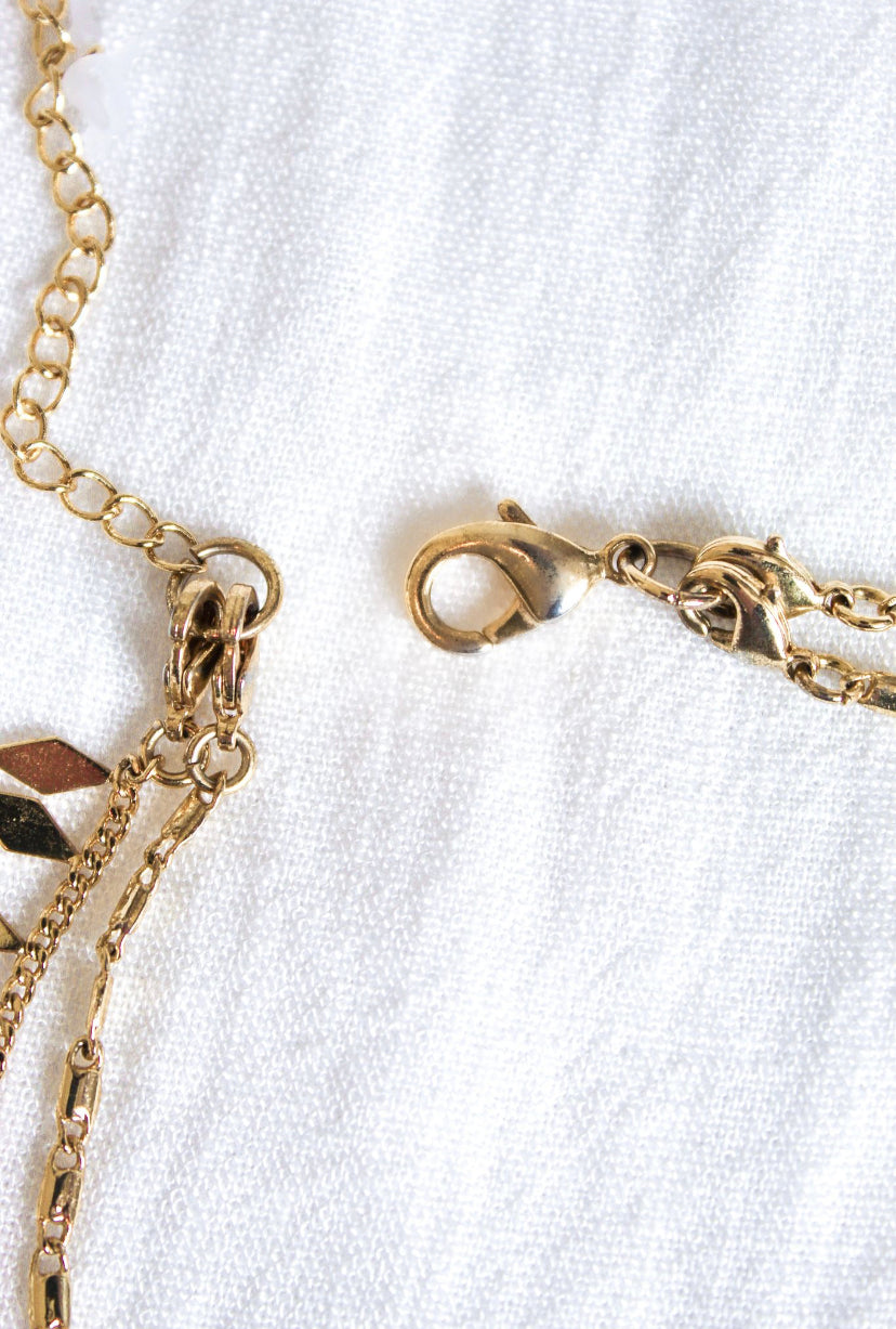 Close-up of the Fisher Necklace by Kinsey Designs Archives, featuring a 14k gold plated clasp and chain on a white textured fabric—ideal for layering.