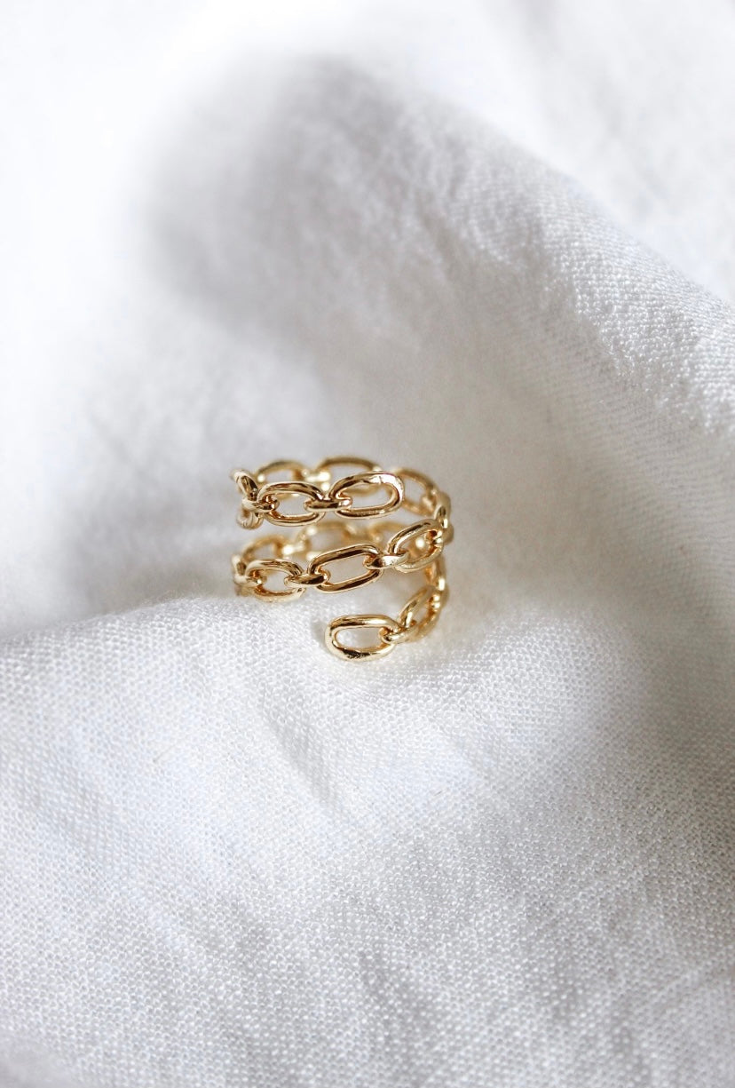 The Peyton Ring by Kinsey Designs, a gold plated chain ring, is shown on a white textured fabric background—ideal for stacking and adding a modern touch to your style.