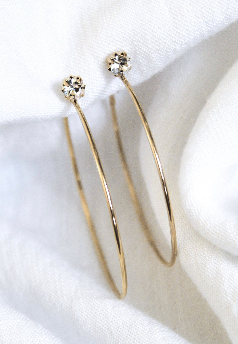 The Ashton gold plated hoop earrings by Kinsey Designs Archives feature small round cubic zirconia studs and are elegantly displayed on white fabric.