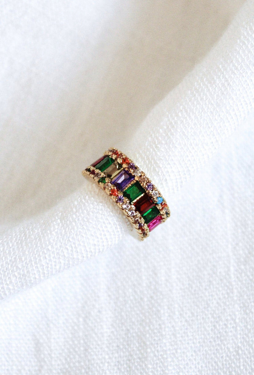 The Clementine Ear Cuff by Kinsey Designs Archives features multicolored rectangular gemstones and sparkling Cubic Zirconia, displayed on white textured fabric.