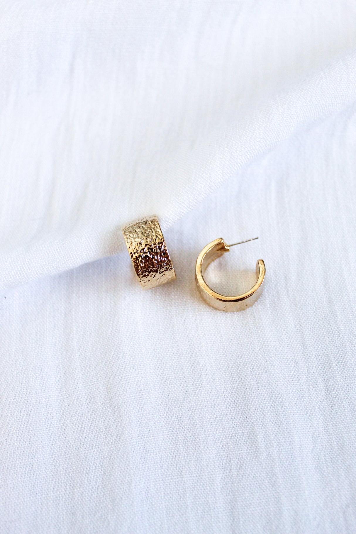 The Fawn Hoop by Kinsey Designs Archives features gold-plated brass with a textured finish, styled on white fabric. A Kinsey favorite for effortless elegance.