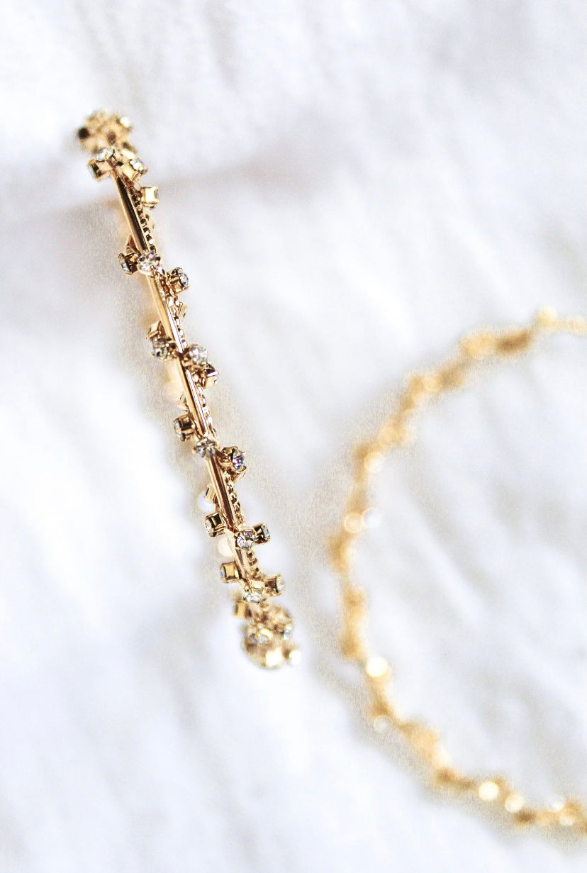 Close-up of two Staci Hoop bracelets by Kinsey Designs Archives, featuring delicate gold plating and small sparkling cubic zirconia crystals on a white fabric background.