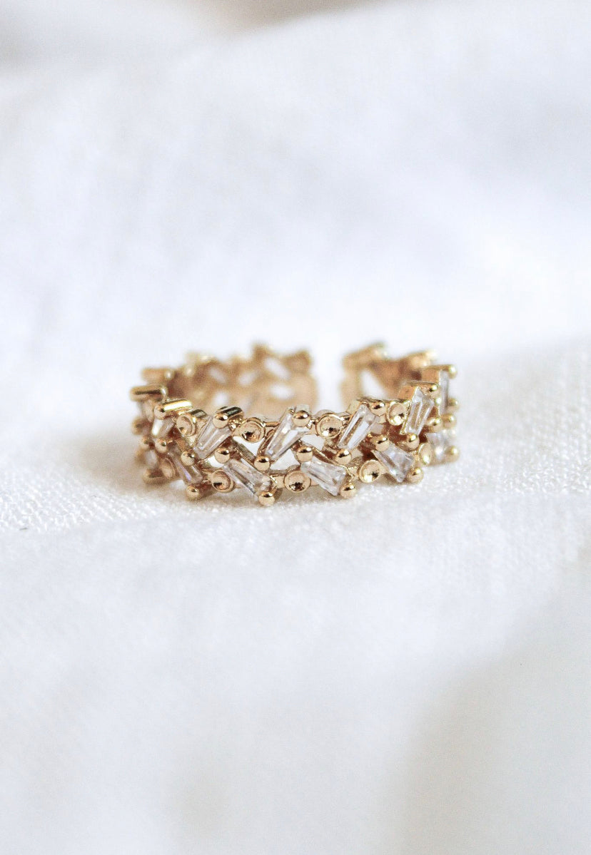 The Rylan Ring by Kinsey Designs Archives features an intricate, textured gold-plated design and is adjustable to fit sizes 7-8, shown resting on a white fabric background.