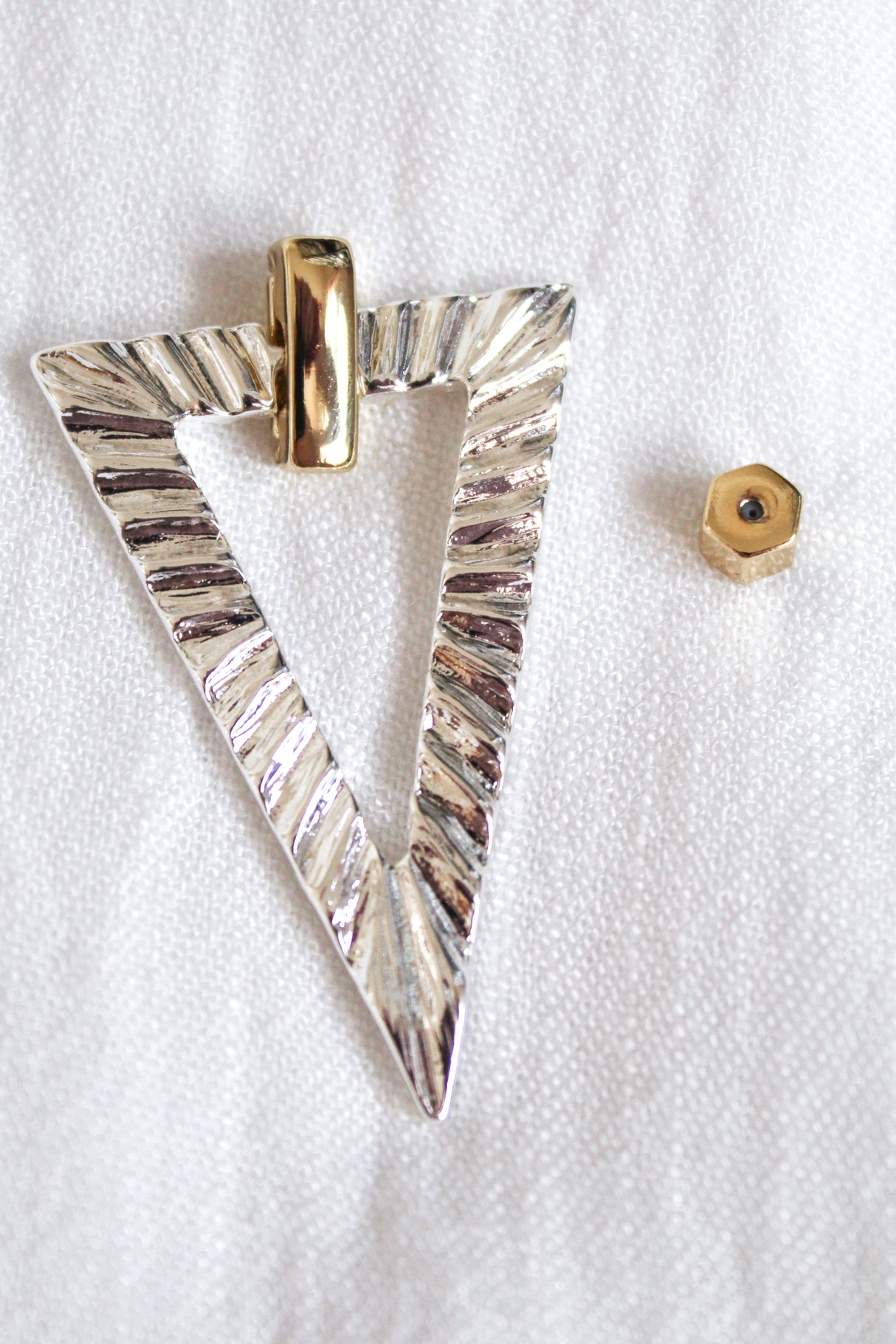 The Colin Earring by Kinsey Designs features a textured silver triangle pendant with a gold bail and a small gold hexagonal bead—ideal for pairing with your favorite gold filled earrings.