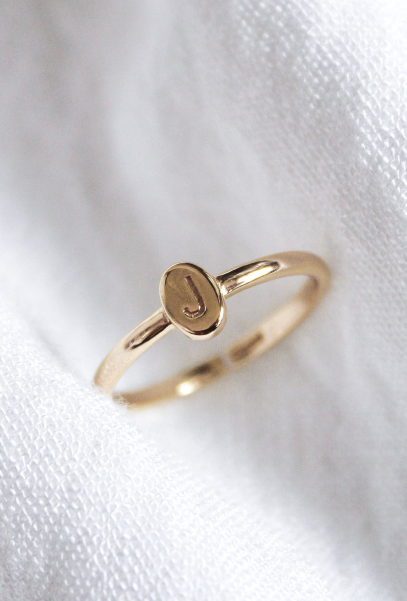 The Kinsey Designs Collection Kinsey Initial Ring features an engraved letter "J" on a circular face, shown resting on white fabric.