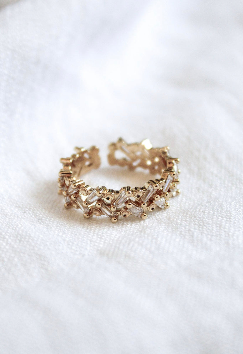 The Rylan Ring by Kinsey Designs Archives features intricate, textured gold plating and rests on a white fabric background. This adjustable ring fits sizes 7-8.