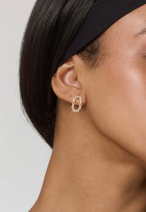 Close-up of a person wearing Kinsey Designs Everly Post textured gold filled earrings with a black headband, perfect for discovering unique styles at a sample sale.