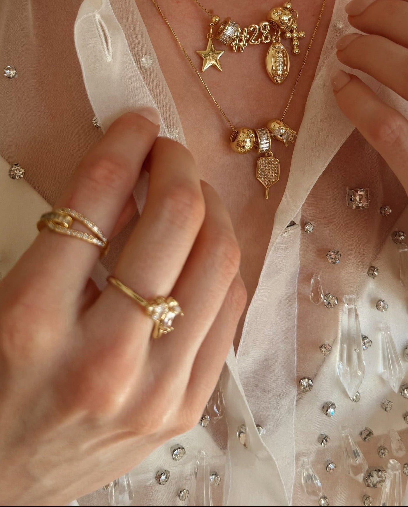 Close-up of hands wearing gold jewelry with a soft, blurred background