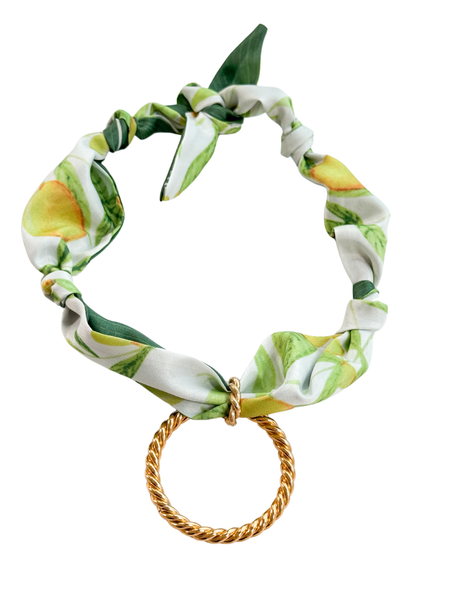 The Arbruzzo Scarf Necklace by Kinsey Designs features a peach print and a twisted gold ring pendant, shown on a white background.