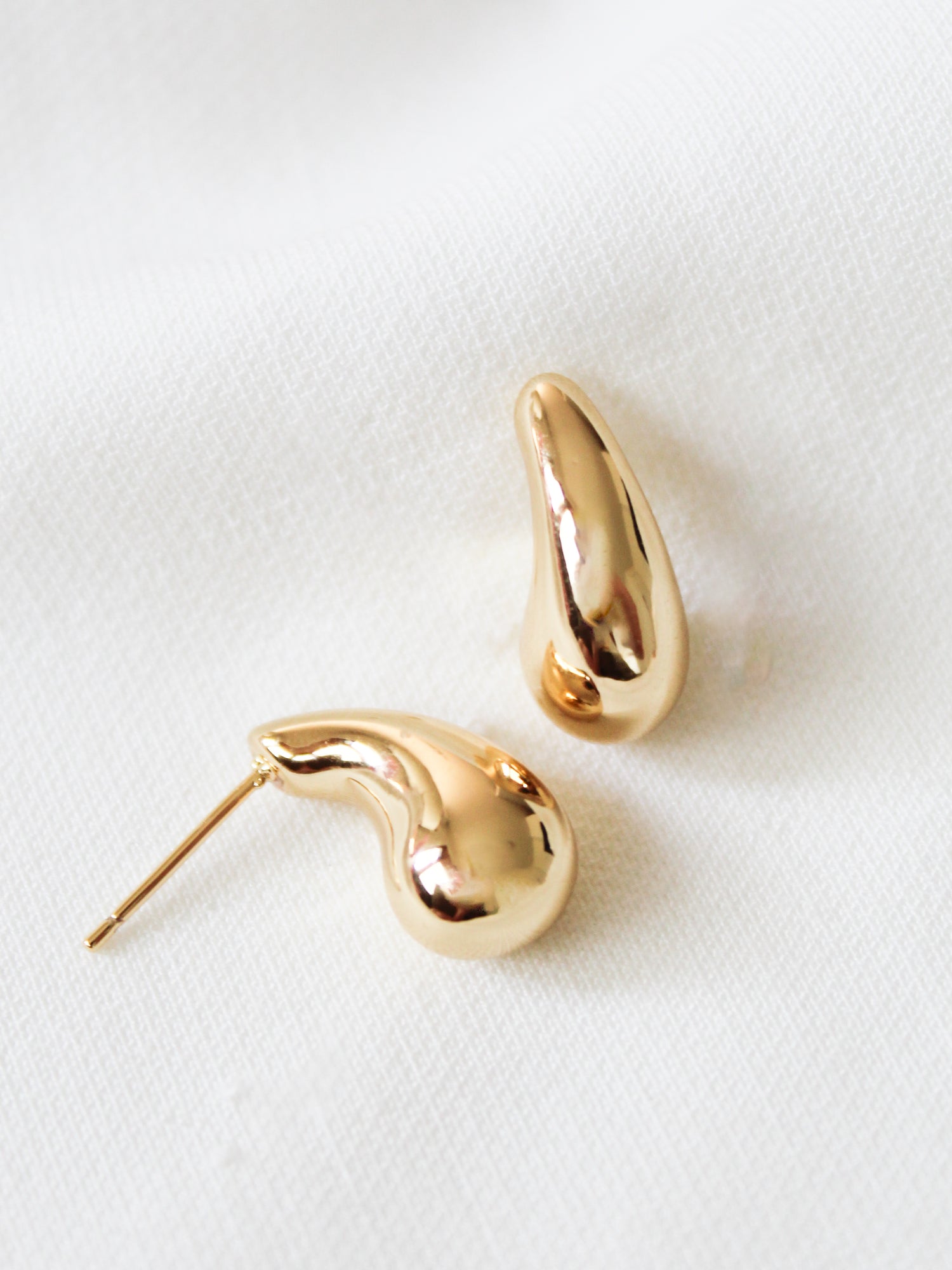 The Kinsey Designs Baby Drop Post earrings are two gold filled, abstract-shaped studs measuring .75" long, shown on a white textured fabric background.